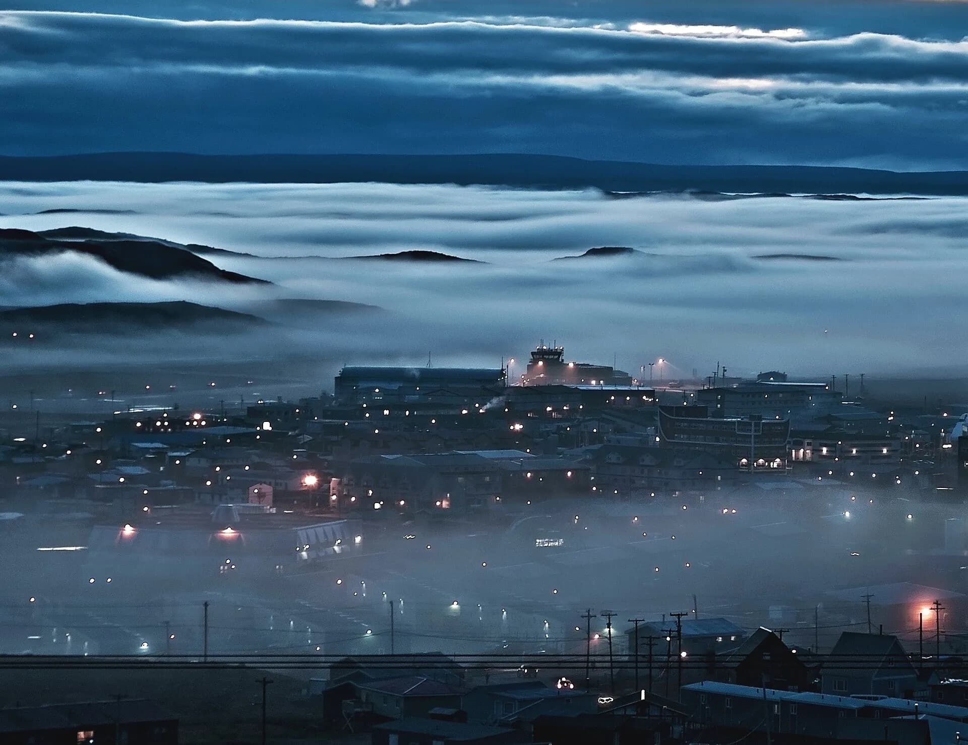Iqaluit au crépuscule, les lumières de la ville sous un banc de brume
